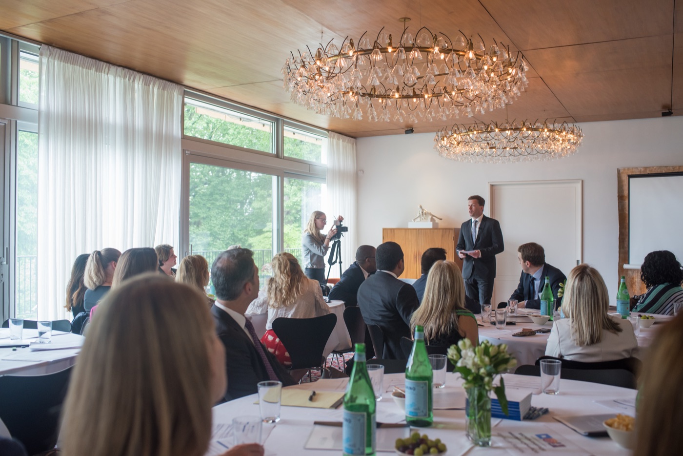 A speaker addressing guests seated at round tables